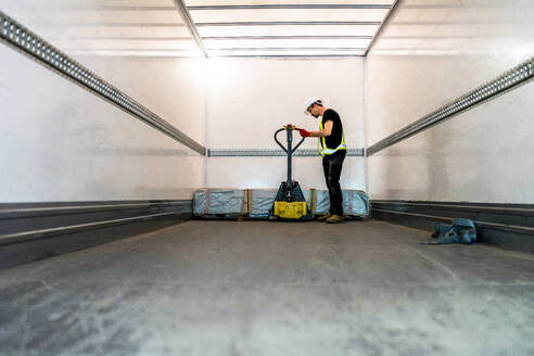 Worker with pallet jack loading in cargo container - DLTSF03806