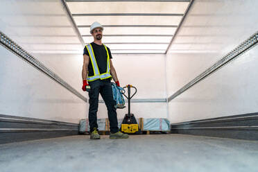 Worker standing near pallet jack inside cargo container - DLTSF03807
