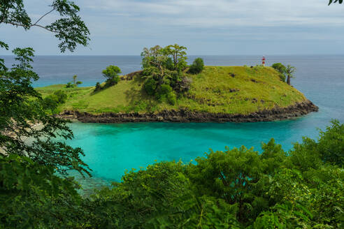Idyllic turquoise waters surround Ilheu das Cabras islet, with a lighthouse atop, off the lush coast of São Tomé - ADSF52964