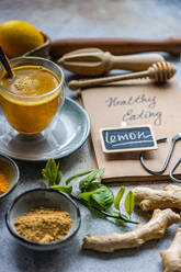 Ein köstlicher goldener Kurkuma-Tee, Zutaten und ein Konzept für gesunde Ernährung auf einem rustikalen Tisch - ADSF53006