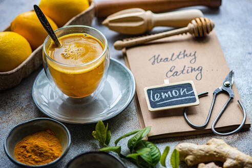 A healthy turmeric lemon drink amidst fresh ingredients and Healthy Eating notebook on a textured surface - ADSF53007