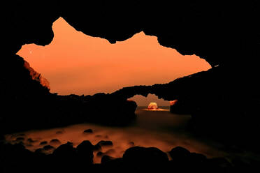 Silhouettierte Vulkanbögen umrahmen einen leuchtend orangen Himmel in der Abenddämmerung auf der Insel El Hierro - ADSF53163