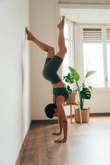 Schönes sportliches Mädchen beim Yoga-Training im Fitness-Studio. Junge Trainerin mit kurzen Haaren, die Yoga- und Acroyoga-Posen ausführt und sich für den Kurs aufwärmt. Konzepte für einen gesunden Lebensstil und Sportdisziplinen - DMDF10001