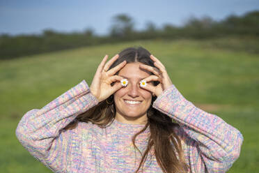 Smiling woman covering eyes with flowers - JSIF00003