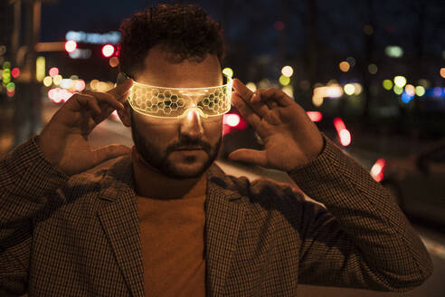 Man wearing smart glasses at night - UUF31517