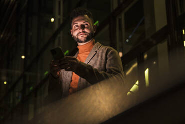 Man holding smart phone at night - UUF31522