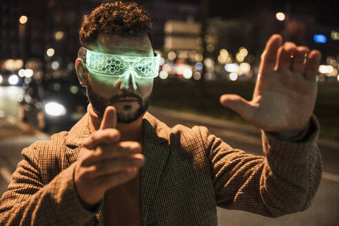 Man gesturing and wearing smart glasses on road - UUF31532