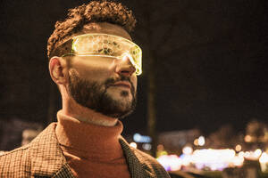 Man wearing smart glasses under sky at night - UUF31535