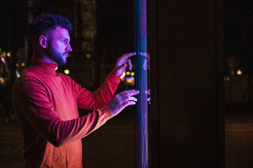 Man using touch screen kiosk at night - UUF31536