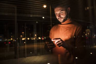 Man using mobile phone seen through glass - UUF31554