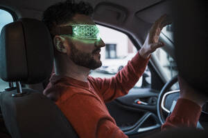Man wearing green smart glasses and gesturing in car - UUF31566