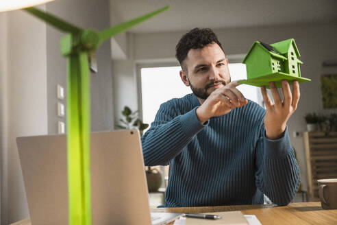 Architect examining model house at home office - UUF31576