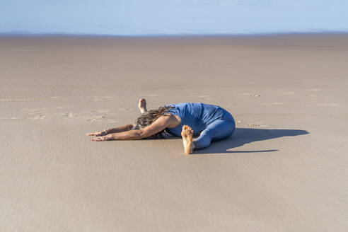 Flexible Frau übt Straddle-Pose auf Sand am Strand - JSIF00012