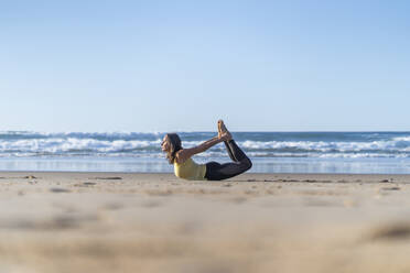 Flexible reife Frau übt Bogen-Yoga-Pose am Strand - JSIF00015