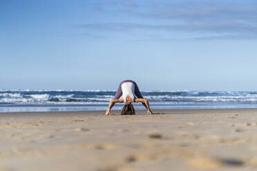 Frau, die sich bückt und am Strand Yoga übt - JSIF00019