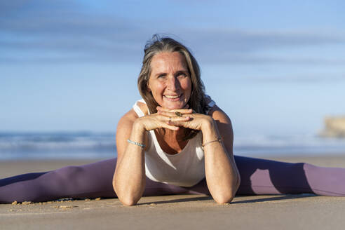 Glückliche reife Frau übt Yoga am Strand - JSIF00021
