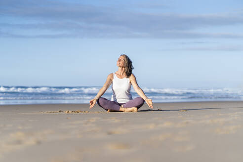 Frau übt Lotus-Position sitzend auf Sand am Strand - JSIF00022