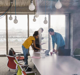 Business colleagues discussing over laptop at table in office - UUF31598