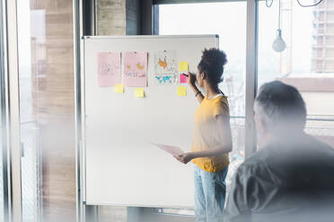 Young businesswoman discussing business plan with colleague in office - UUF31604