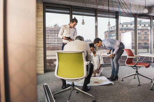 Businessman sitting on chair and discussing with colleague at office - UUF31615