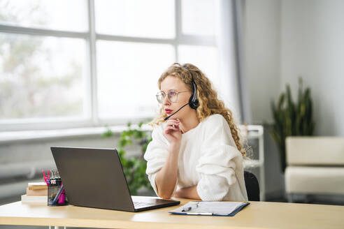 Kundendienstmitarbeiter, der über ein Headset im Callcenter spricht - MDOF01837