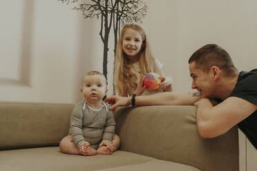 Toddler sitting near family on sofa at home - OSF02430