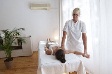 Osteopath massaging patient's arm in treatment room - AAZF01580