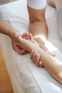Osteopath behandelt Druckpunkte auf der Handfläche des Patienten im Behandlungsraum - AAZF01595