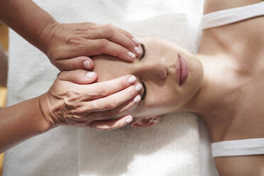 Hände des Therapeuten massieren den Kopf des Patienten im Behandlungsraum - AAZF01632