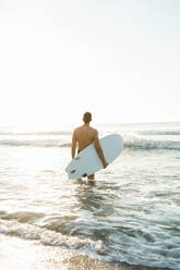 Junger Mann hält Surfbrett am Strand - AAZF01667