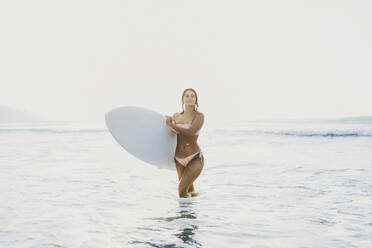 Woman wearing bikini and walking in water at beach - AAZF01673