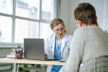 Doctor having discussion with patient at desk in office - MDOF01874