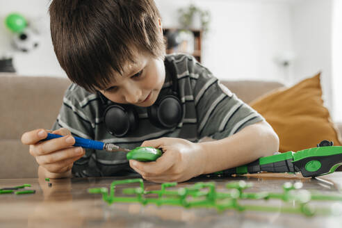 Boy using screwdriver and making toy model at home - ELMF00039
