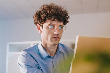 Serious businessman working on laptop in office - YTF01890