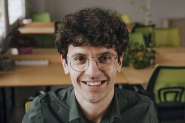 Smiling businessman wearing eyeglasses in office - YTF01907