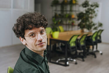 Businessman with curly hair wearing eyeglasses in office - YTF01915