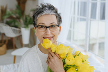 Smiling woman with bunch of tulips at home - YTF01977