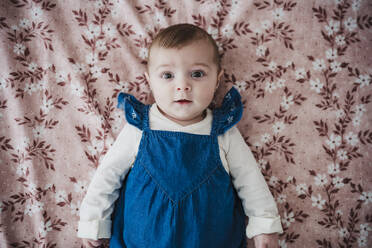 Cute baby girl lying on bed in bedroom - EBBF08799