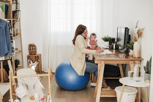 Arbeitende Mutter mit kleinem Mädchen im Home Office - EBBF08823