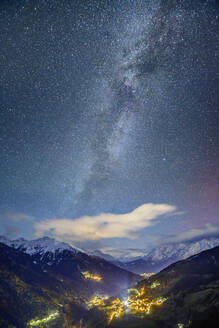 Austria, tyrol, Fliess, Milky Way galaxy against starry night sky over illuminated town in Lechtal Alps - ANSF00782