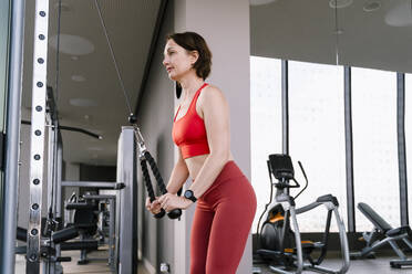 Woman working out on cable crossover machine at gym - NDEF01574