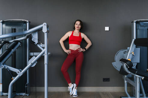 Confident woman standing near exercising equipment at gym - NDEF01576