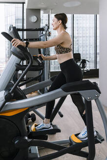 Mature woman exercising on elliptical trainer at gym - NDEF01578