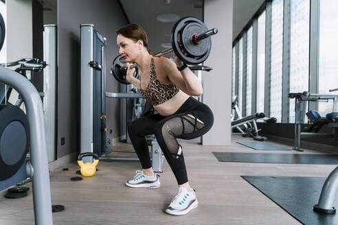 Mature woman exercising with barbell at gym - NDEF01580