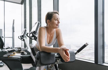 Mature woman leaning on hyperextension machine at gym - NDEF01605