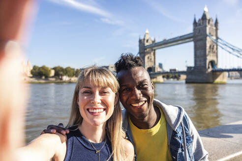 Glückliche multirassische Freunde machen ein Selfie mit der Tower Bridge im Hintergrund - WPEF08493