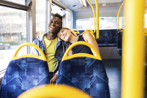 Happy multiracial couple traveling in double-decker bus - WPEF08515