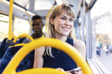 Aufgeregte junge Frau, die in einem Doppeldeckerbus reist - WPEF08520
