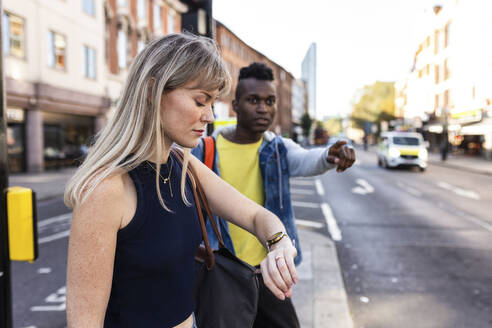 Frau überprüft die Zeit mit einem Freund auf der Straße in der Stadt - WPEF08525