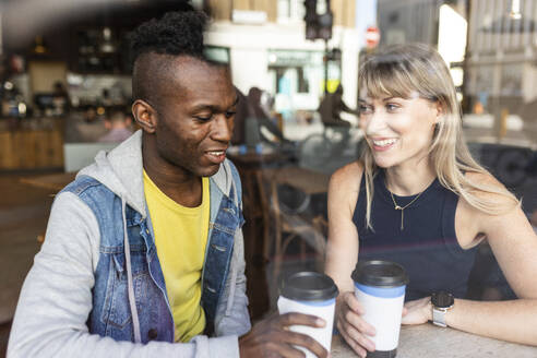 Glückliche multirassische Freunde, die im Café sitzend Kaffee genießen - WPEF08526